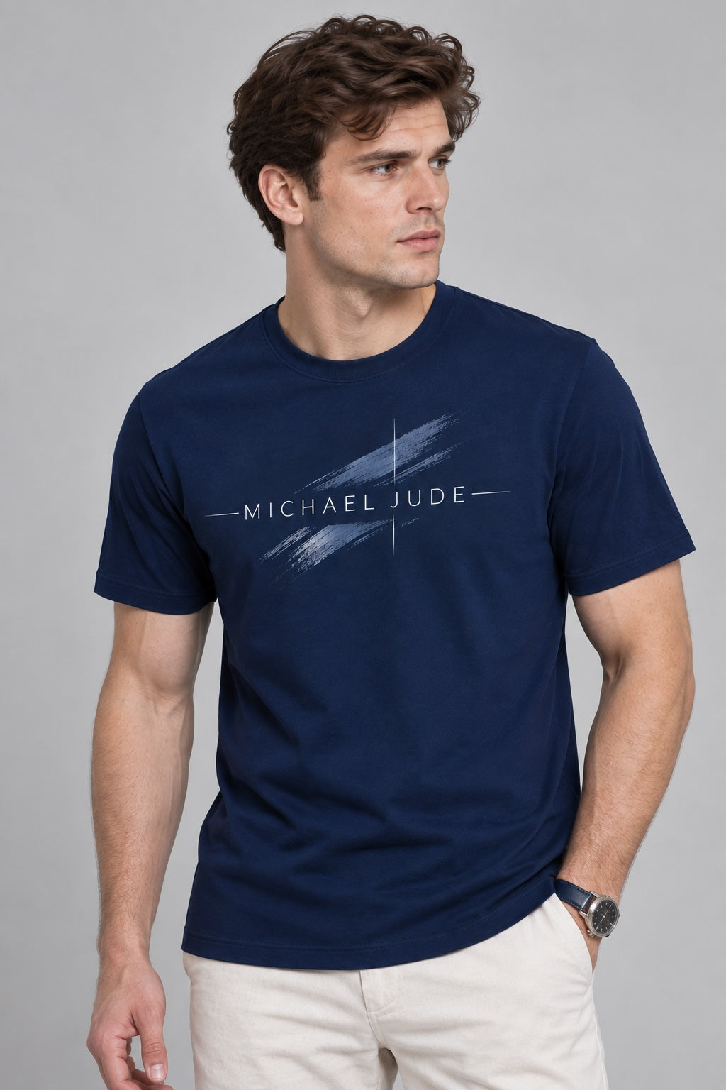 A man wearing a Michael Jude navy blue crewneck t-shirt with a white artistic brushstroke graphic on the chest.